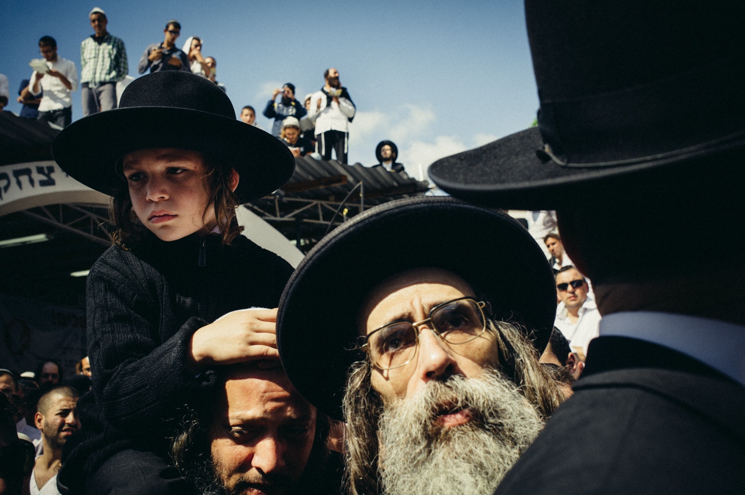 Young Hasid sits on the shoulders of his father in prayer.