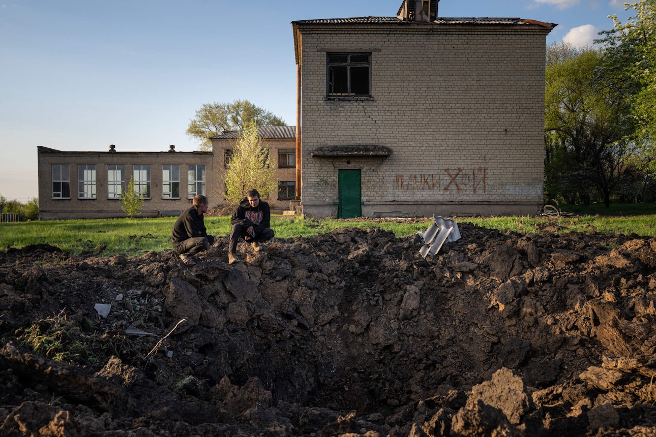 Підлітки дивляться на воронку після російського ракетного обстрілу на подвір’ї школи. Добропілля, 28 квітня 2022 року.